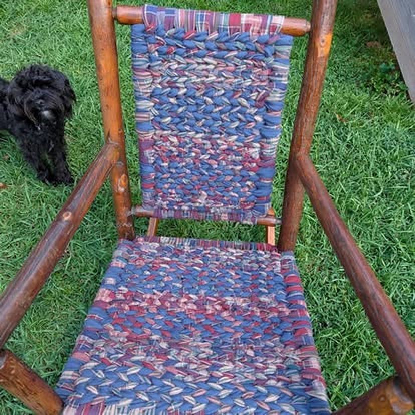 Rustic rocking chair with a red, white and blue woven seat and back